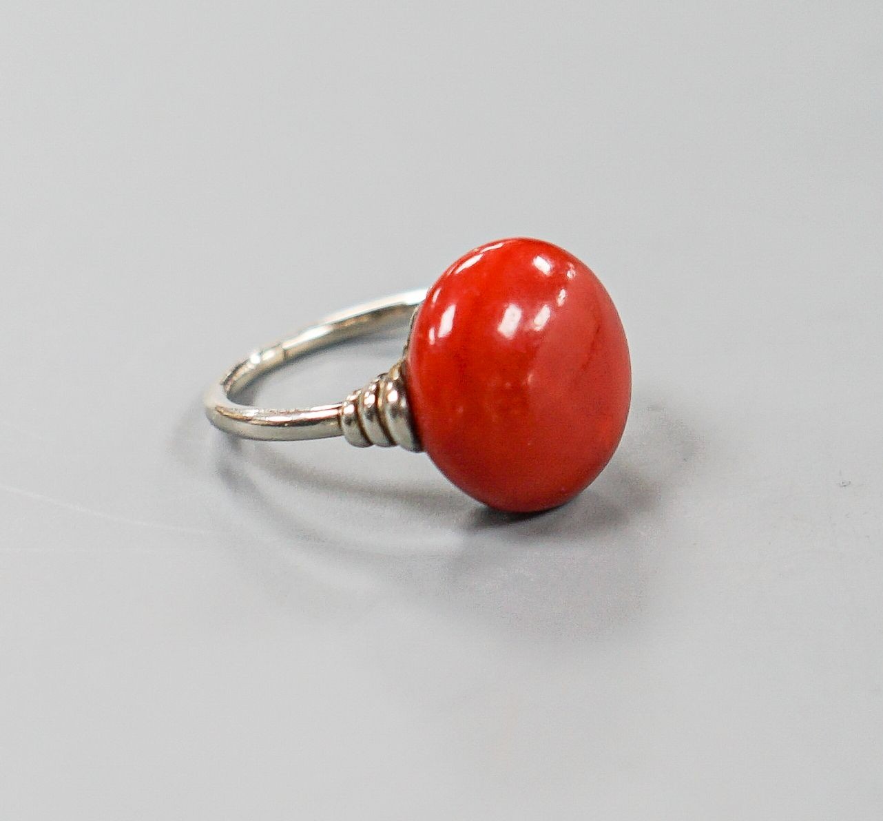 A 585 white metal and stained? cabochon coral set dress ring, size I, gross weight 5.5 grams.